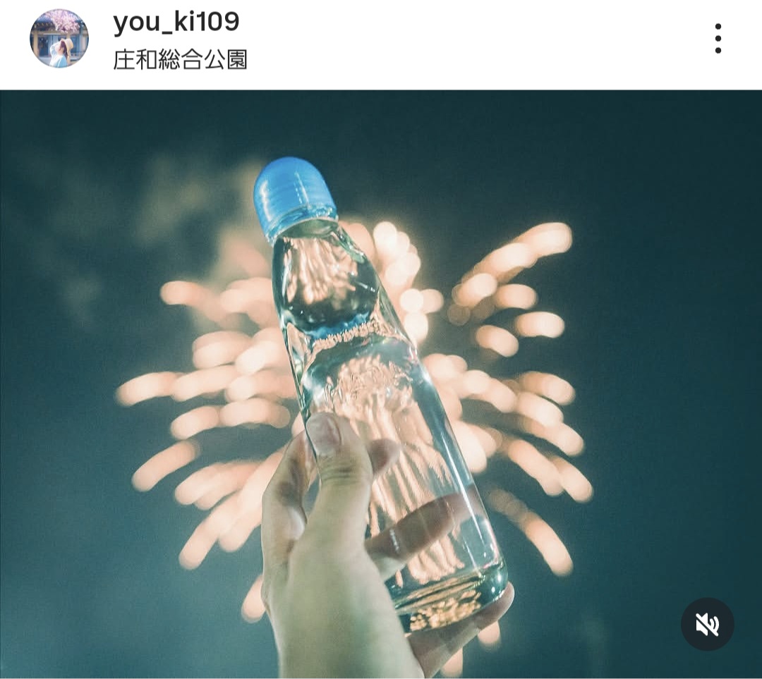 花火を背景に、瓶ラムネを持っている写真