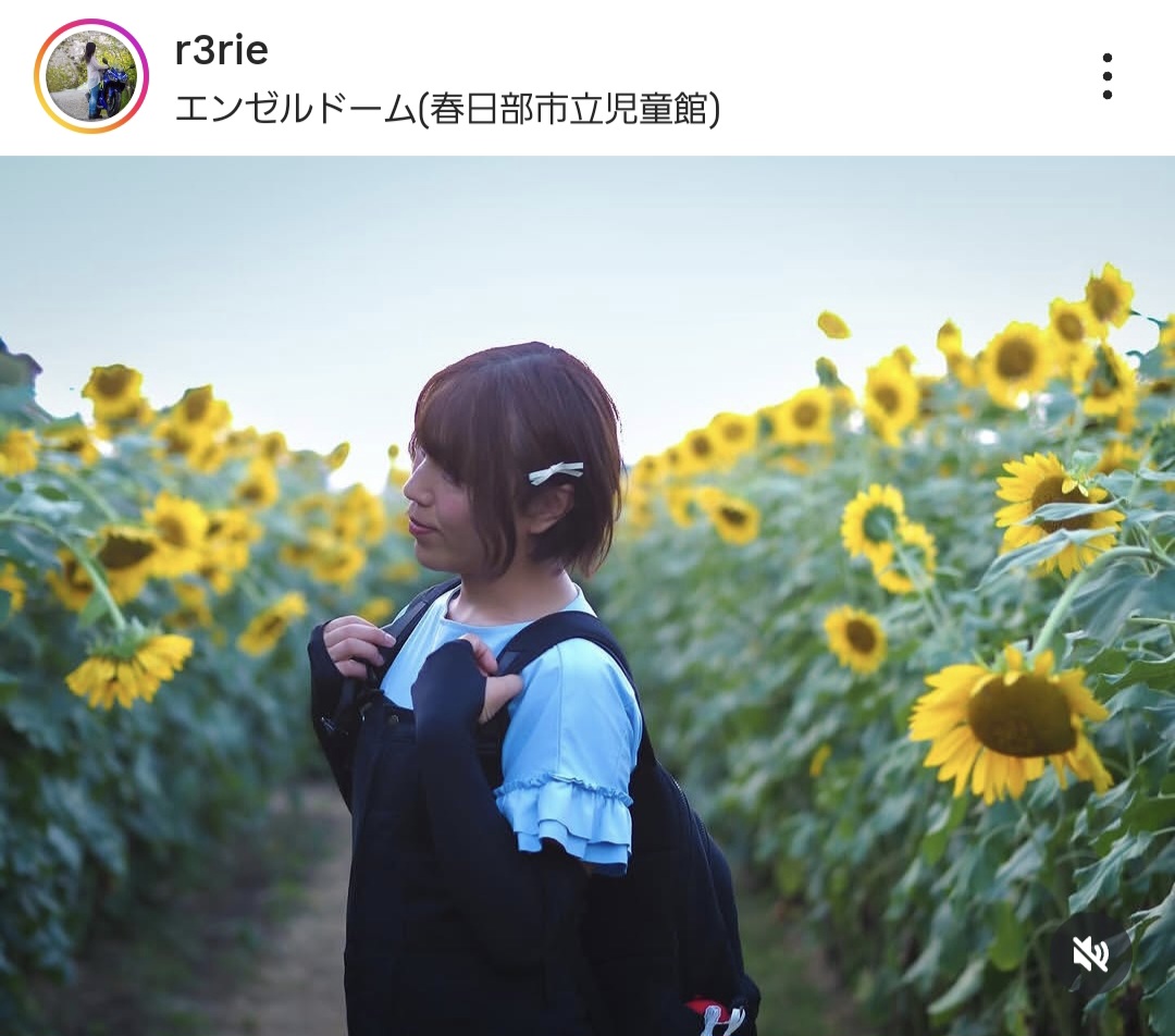 ひまわり畑の中で人がたたずむ写真