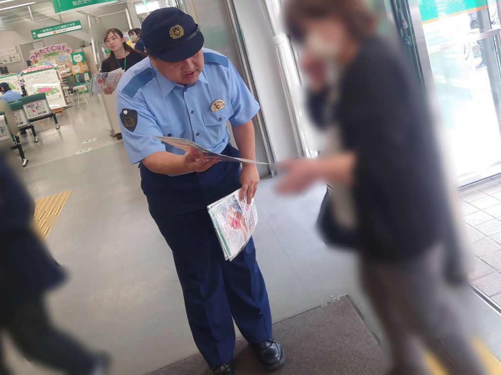 春日部警察署員が銀行来店者に啓発品を渡す様子