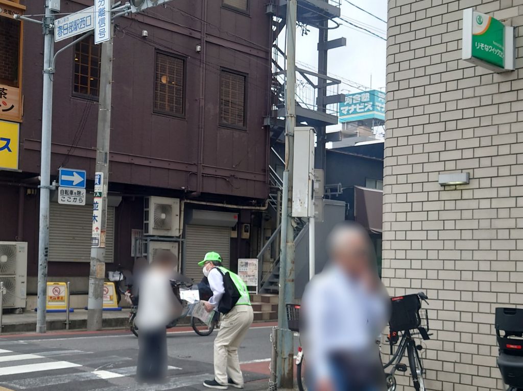 市職員が交差点利用者に啓発品を配布する様子