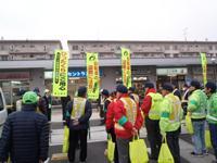 蛍光色のジャケットを着て、手提げバッグを持った数人の男性が並んでいる様子の写真