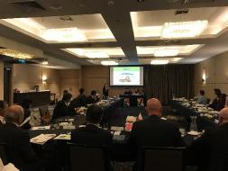 ミーティングにて着席した参加者がスクリーンを見ている様子の写真