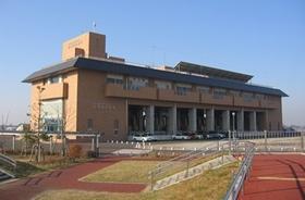 青空の下建つ茶色外壁の龍Q館の北側外観を左斜めから撮影した写真