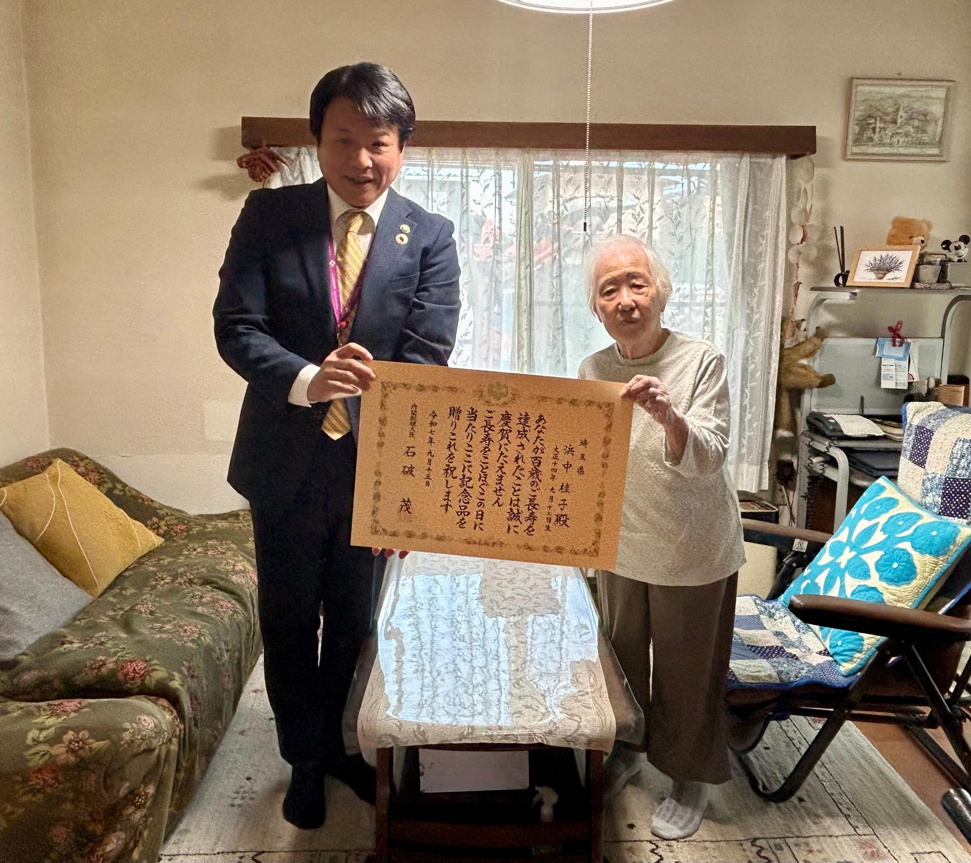 賞状を持っている市長と長寿者