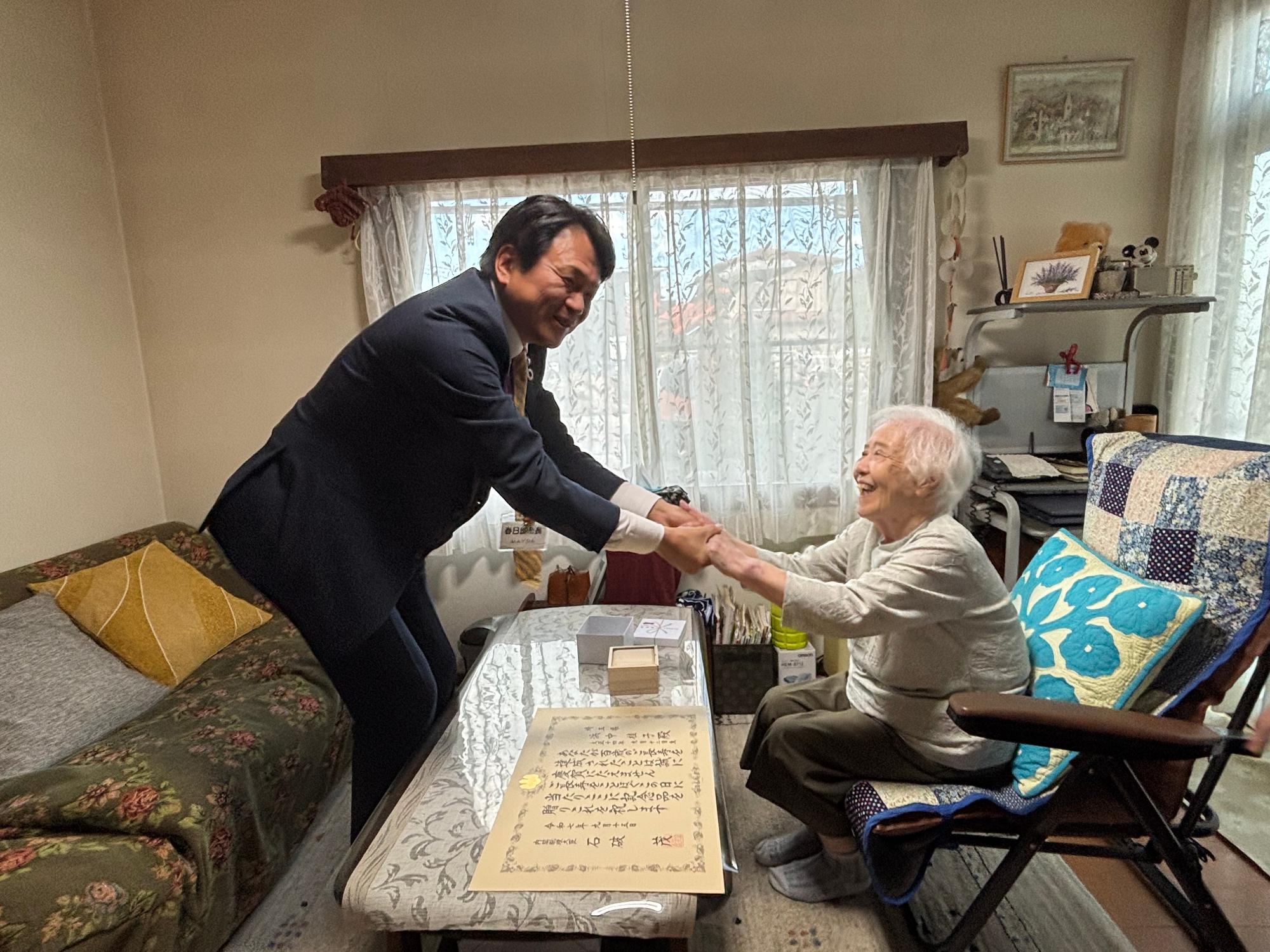 市長が長寿者と握手する様子