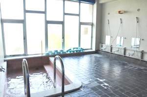 複数台のシャワーと手すり付きの浴槽が設けられた、浴室の内装写真