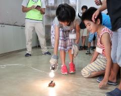 ソーラーカーに白熱灯を当てて走らせている様子の写真