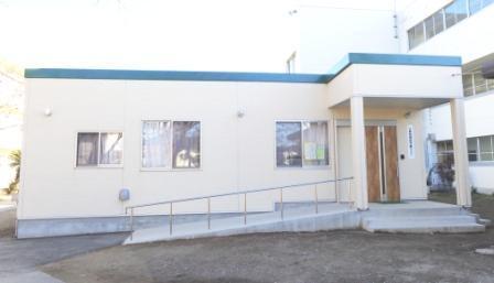 入り口までがコンクリートスロープになっている青色の屋根が特徴的な立野小学校内にある立野放課後児童クラブ3の外観を撮影した写真