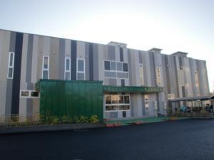 四角形の建物にグレー系の縦じま模様の壁が特徴的な春日部市立武里南保育所外観を左斜め側から撮影した写真