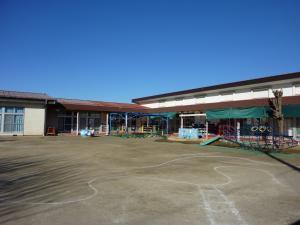 雲一つない晴天の下建つ庄和第2保育所の外観を園庭側から撮影した写真