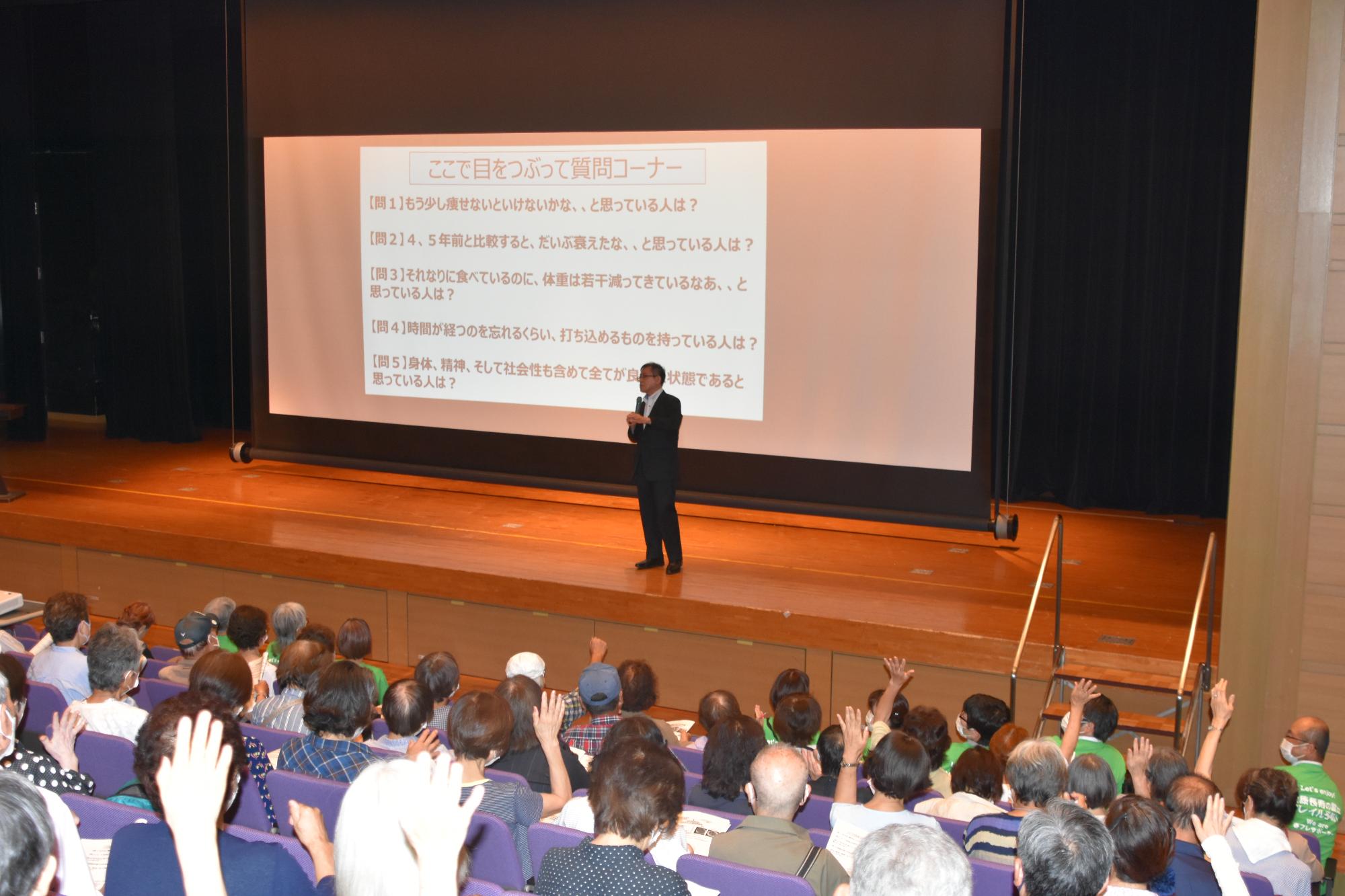 飯島先生が参加者に質問し、参加者が手を上げている様子