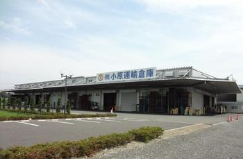 青空の下建つ広々とした小原運輸倉庫の建物の写真