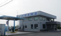 屋根がある入口のある、株式会社 宮本陸運の社屋と給油所の外観の写真