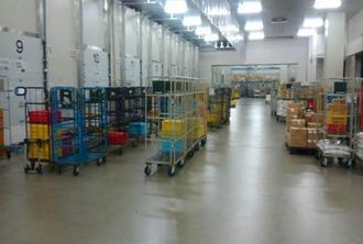 荷物を入れる箱を乗せたカートが並んでいる倉庫の写真
