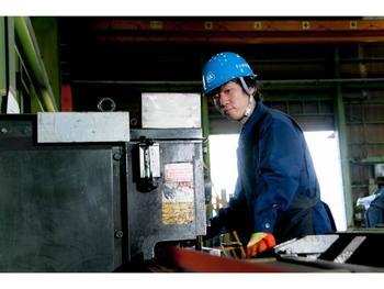 群青色の作業着に水色のヘルメットをし作業をしている男性の写真