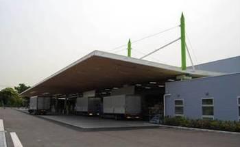 倉庫外部にて、たくさんの大型トラックが並んでいる様子の写真