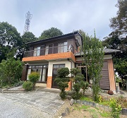 森に囲まれるように建つ農家住宅の写真