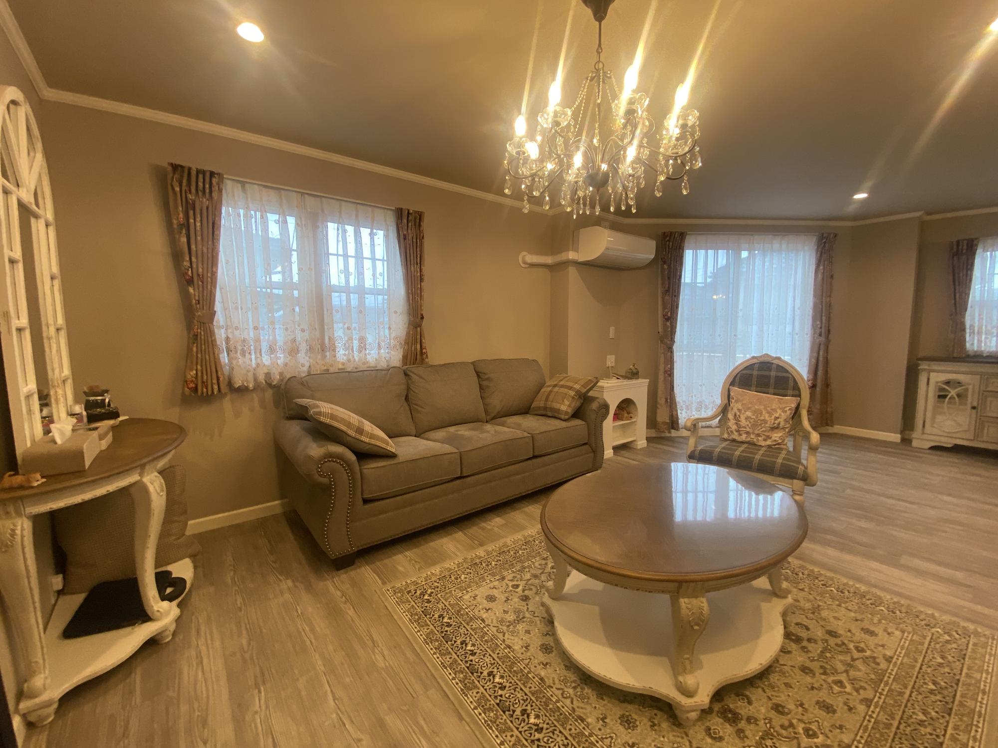 特徴的な大きめな窓とゆったりと座れるソファがあるリビングの写真