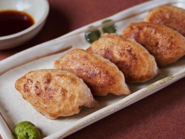 四角い皿にわさびと一緒に提供されている赤沼餃子の写真