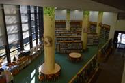 丸い机があり、奥には本棚が並ぶ図書館内を上から見下ろした写真