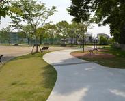 芝生の間を縫って続く広いタイル舗装の歩道の写真