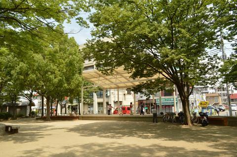 葉の生い茂る木の奥に中央町第4公園のステージがある写真