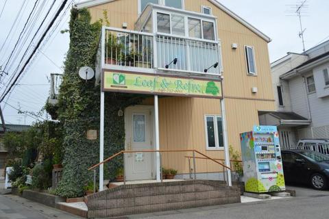 卵色の壁面とアイビーの緑のコントラストが特徴的なリーフ・アンド・リフレ店舗外観の写真