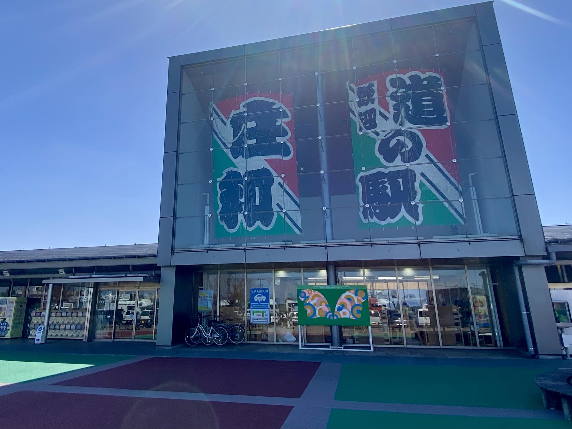 ガラスパネルの中にある筆文字で道の駅「庄和」と書かれたのぼりが特徴的な店舗外観の写真