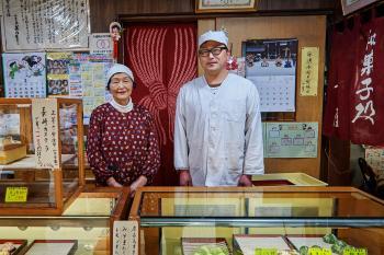 割烹着姿でカメラに向かって微笑む親子の写真