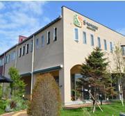 緑に囲まれ、暖かい色合いの外壁をしたエス・テラス外観写真