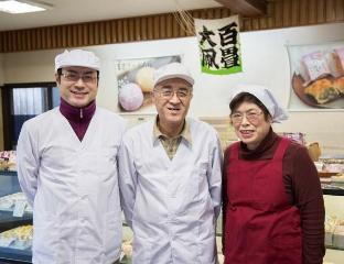 店舗ショーウィンドウ前で一番左から7代目、6代目夫妻と並んで立っている正面写真