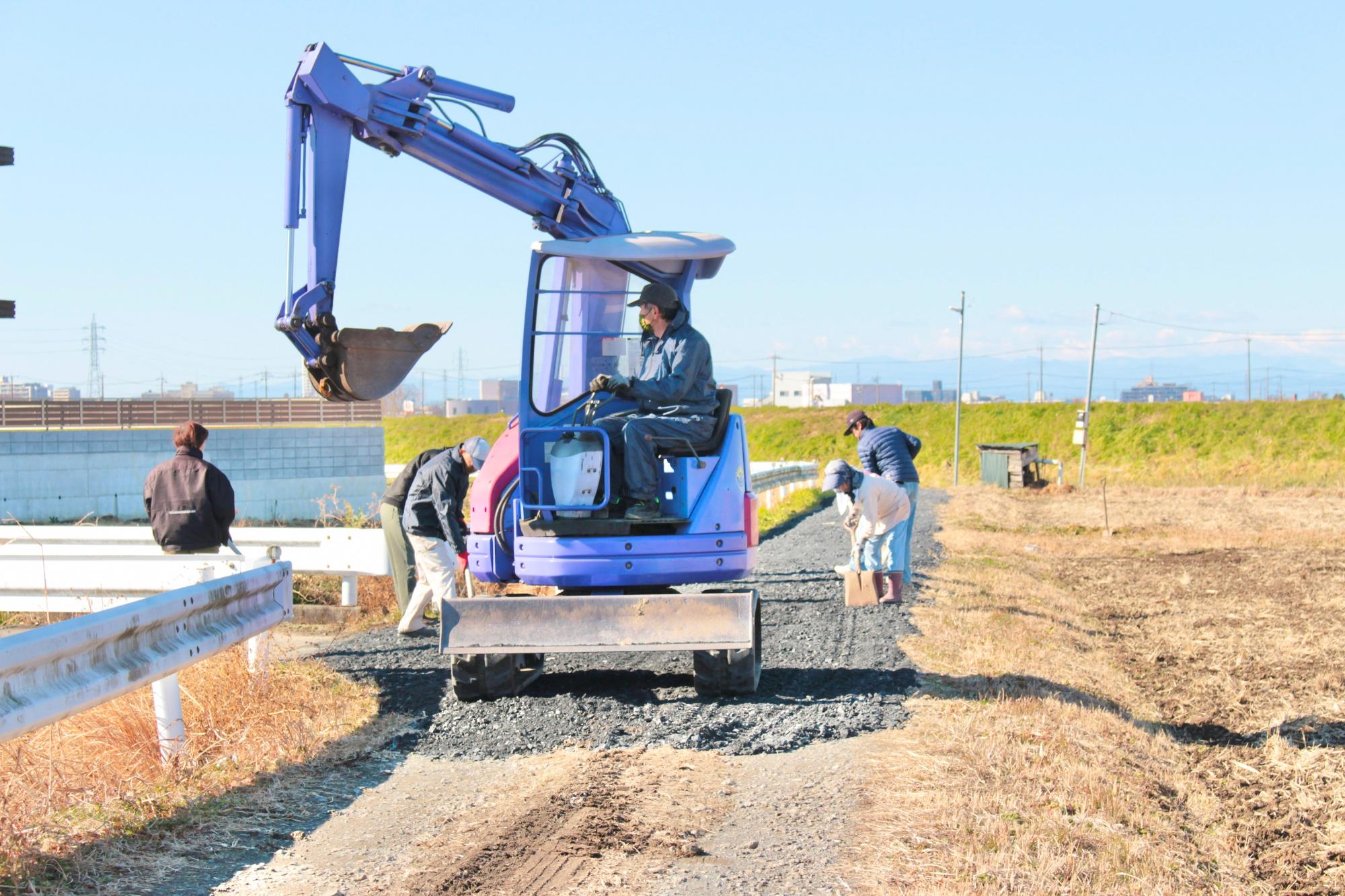 重機と人力で砂利を敷きならす