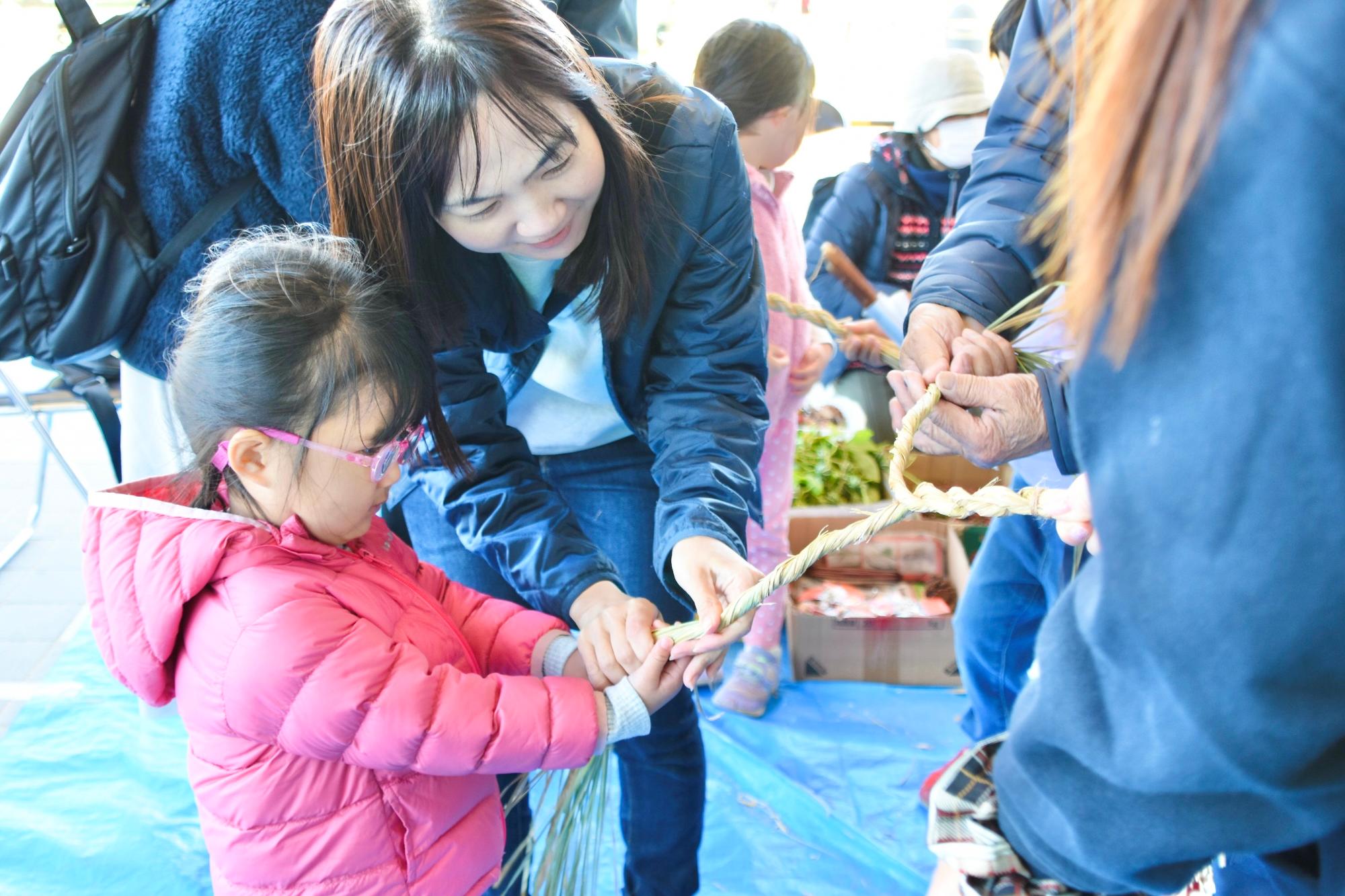 親子で稲わらをねじる様子