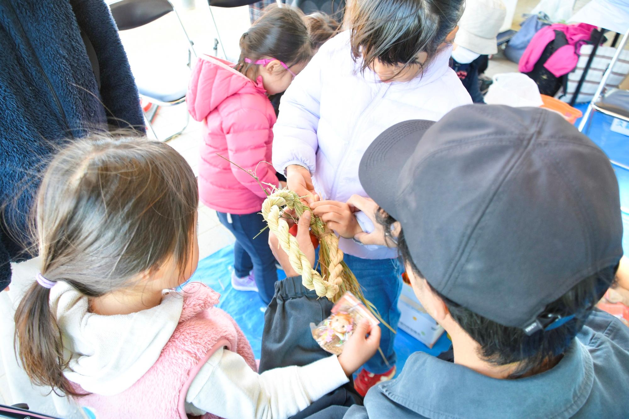 親子で稲わらリースを飾り付ける様子