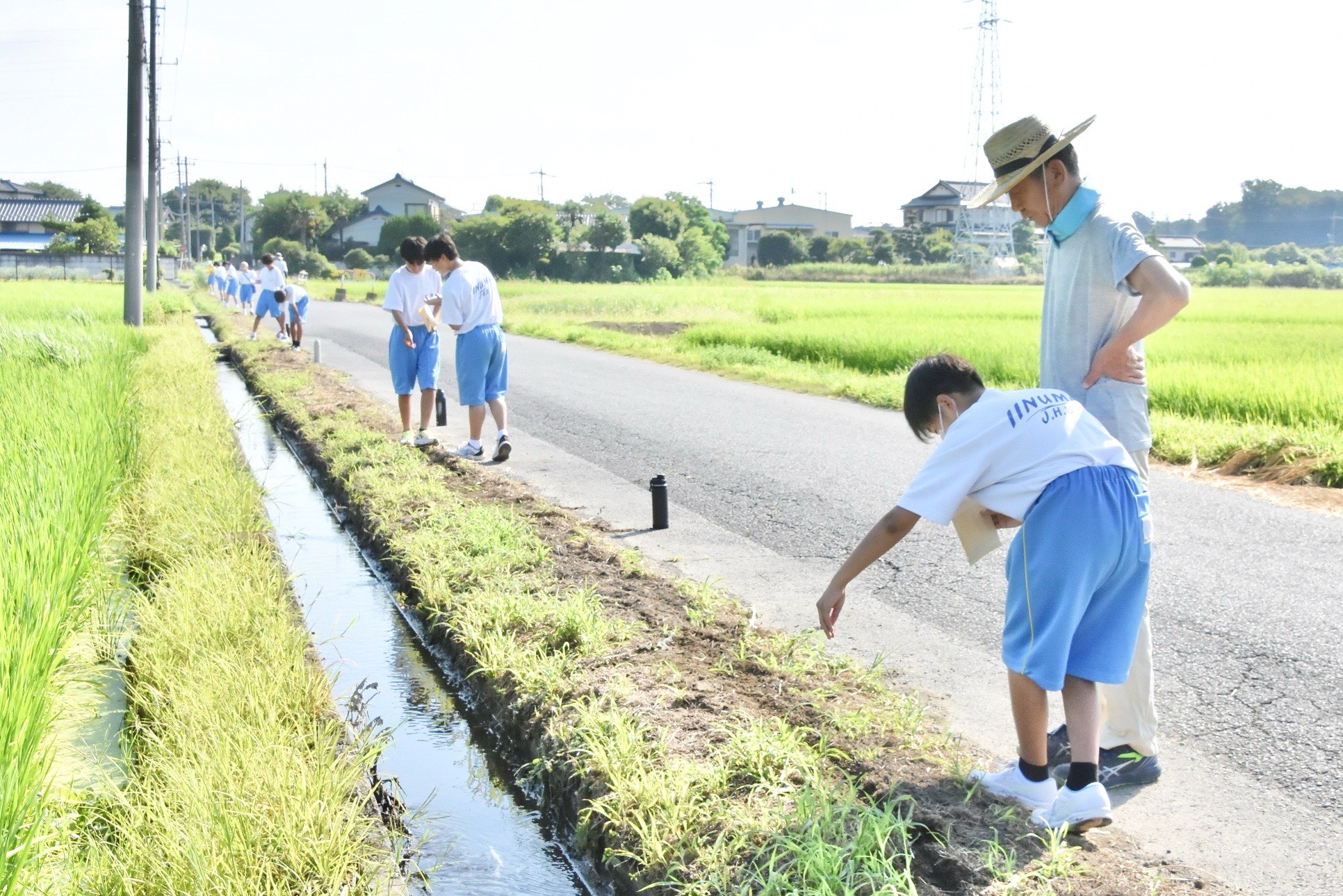地元の人に教わりながら種をまく中学生