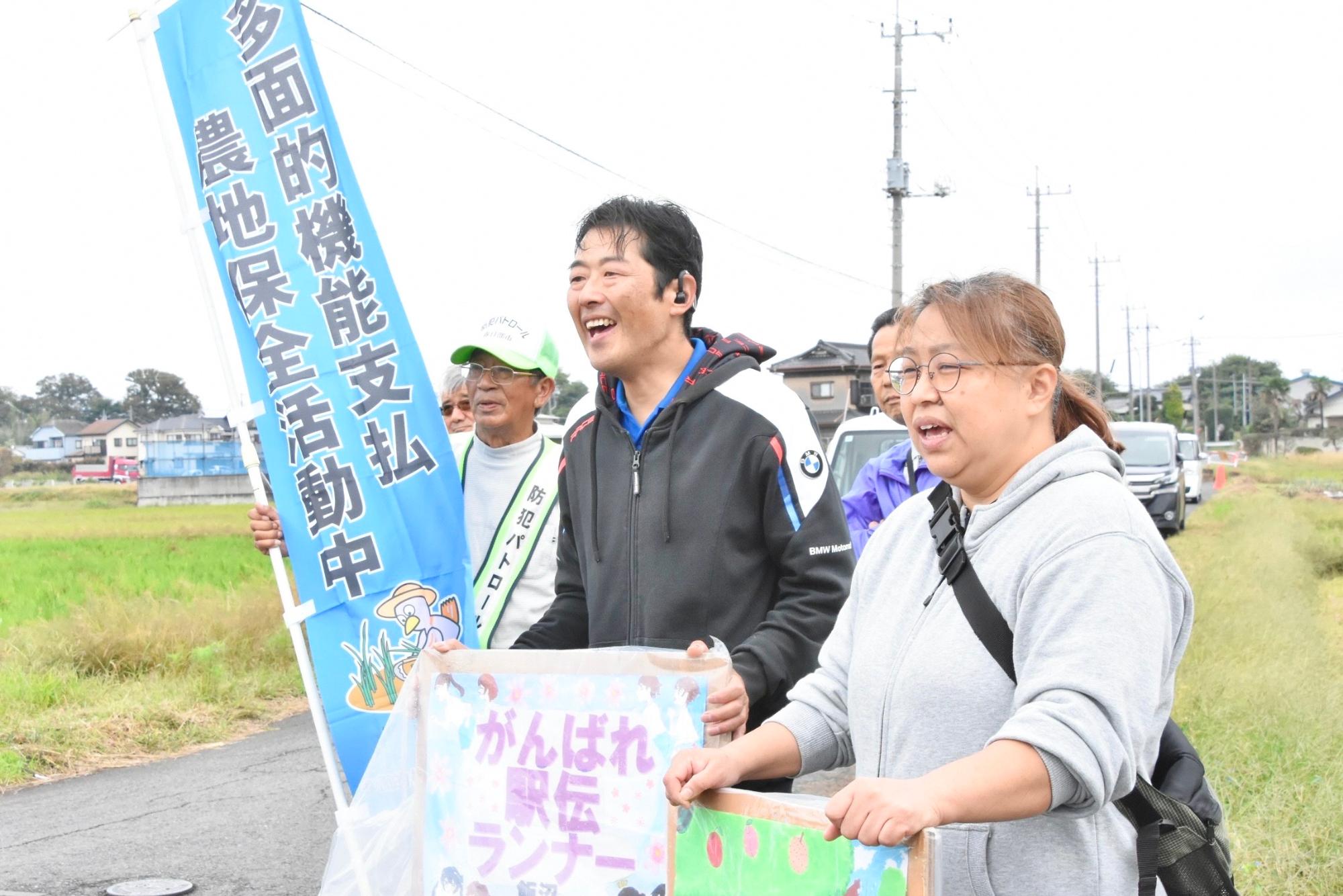 手作りの看板を片手に駅伝ランナーを応援する組合員