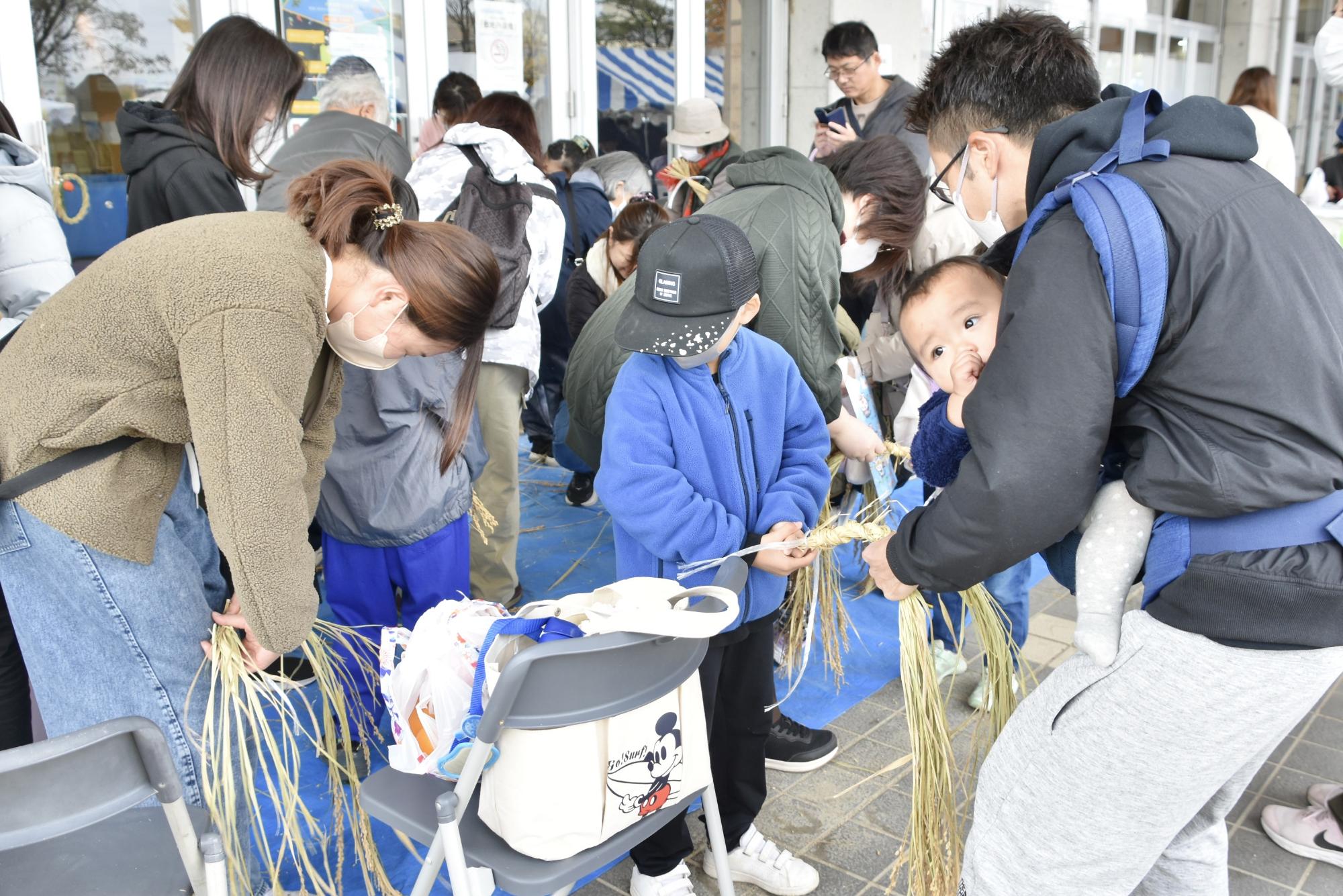 稲わらリースを編む家族