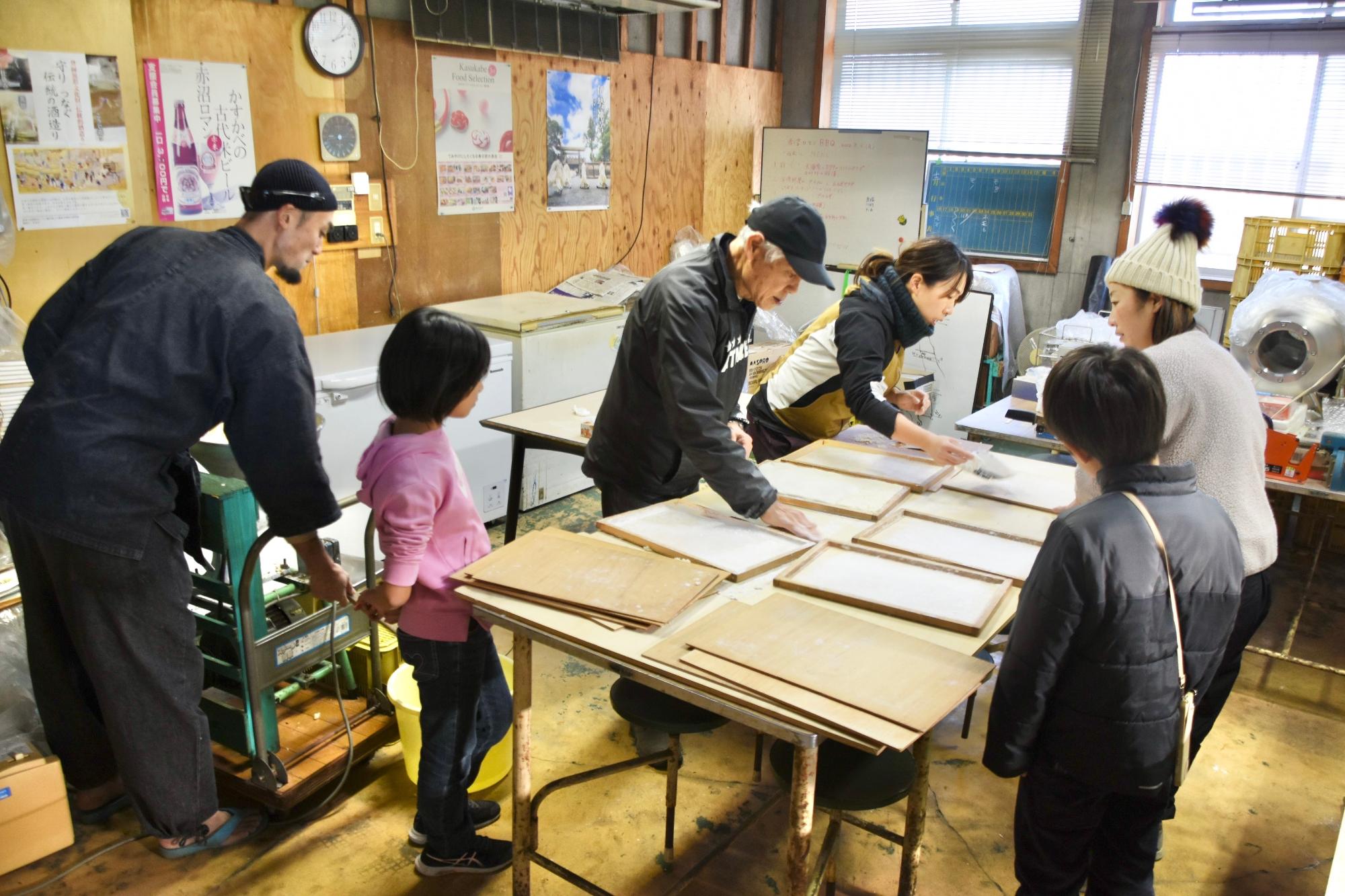 木枠に餅を敷き詰めてのし餅を作る様子