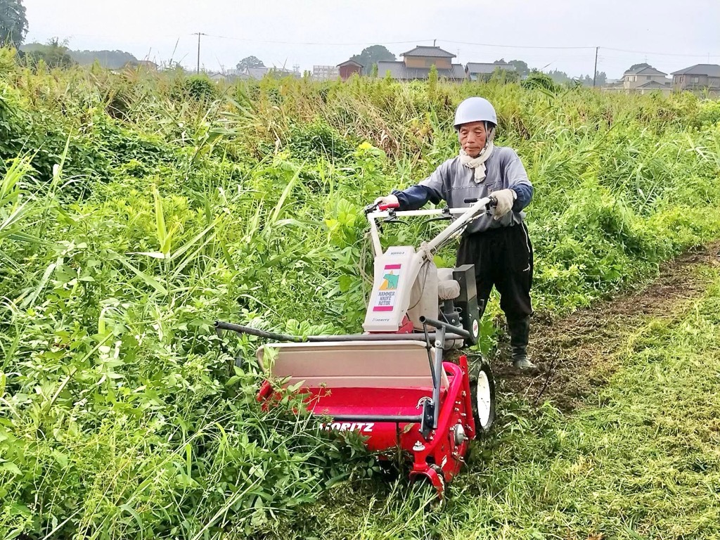 自走式の草刈り機を人が押す様子