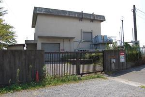 曇り空の下、コンクリートの壁と頑丈な門構えの中に建てられた赤沼ポンプ場の外観の写真