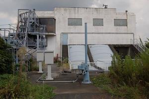 曇り空の下、白い色の建物に多数のパイプが接続されている様子の備後ポンプ場の外観の写真