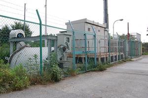 曇り空の下、コンクリートの地面に緑色の網目のフェンスに囲まれている様子の土井ポンプ場の外観の写真