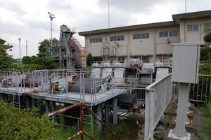 曇り空の元、クリーム色の建物の脇に建っている粕壁ポンプ場の外観の写真