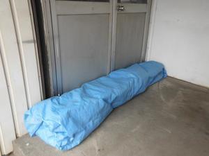 建物の入り口に土のうの代わりとして置かれている、ブルーシートで包まれたプランターを活用した写真