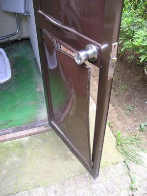 蹴破られ、中が見える状態になってしまった公園のトイレの扉の写真