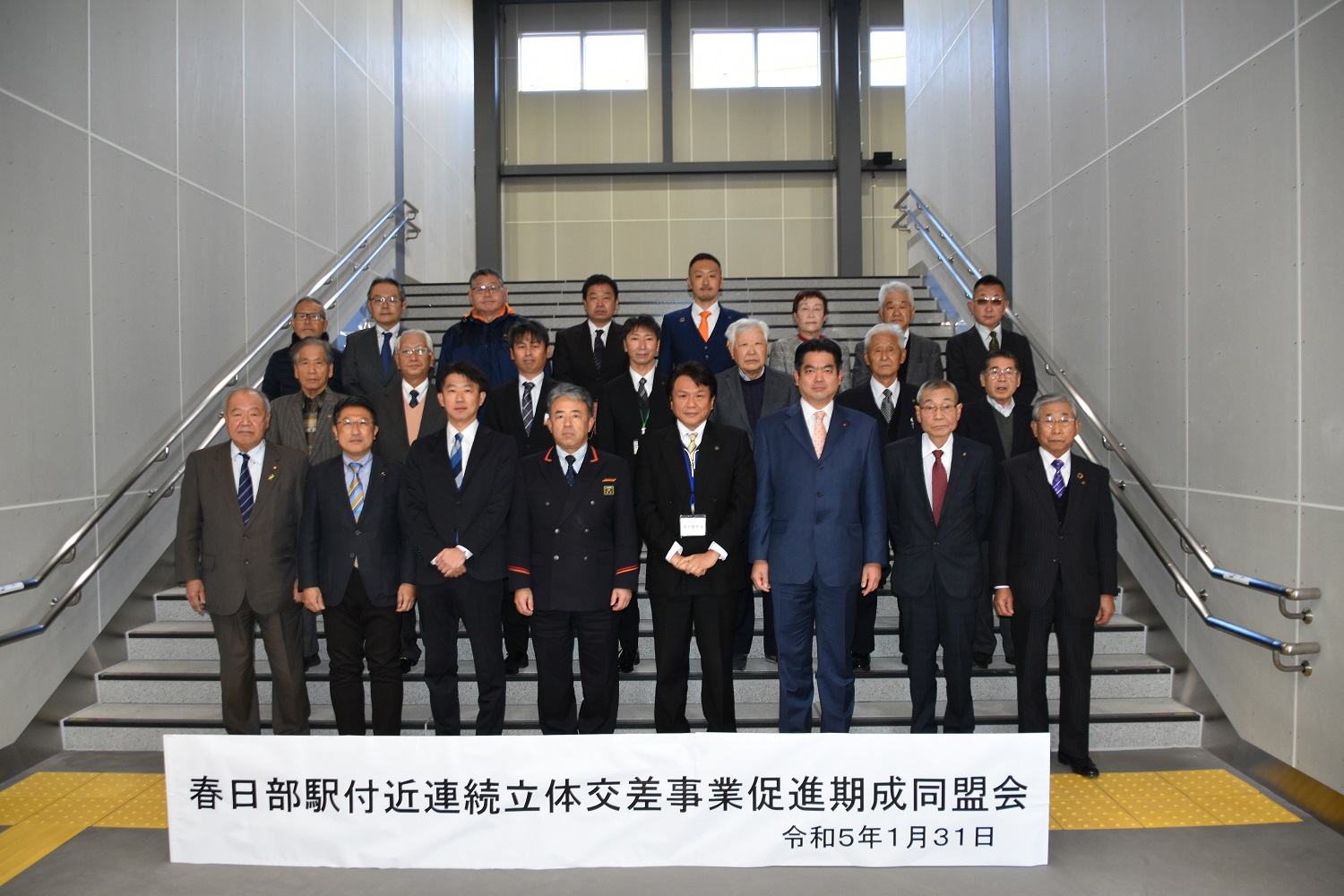 春日部駅付近連続立体交差事業促進期成同盟会と書かれたパネルを前にした、同盟会一同と来賓の記念写真