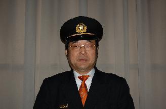 室内にて制帽と制服を着用した連合消防団長須賀 正幸氏の写真