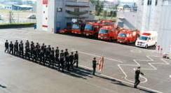 消防車と救急車が並んでいる前で消防団員が消防特別点検を行うにあたり整列して並んでいる様子の写真