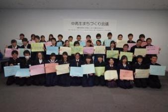 中高生の参加者がそれぞれテーマを描いたカラフルな色画用紙を手にして並んでいる集合写真