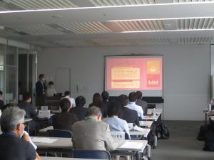 スクリーンに映る取り組み事例を見ながら参加者が話を聞く様子の写真